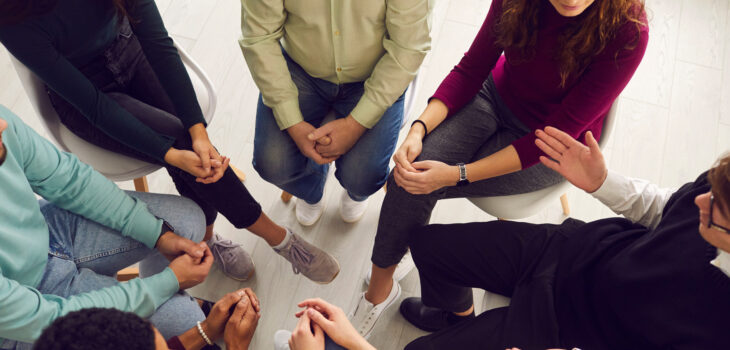 Group of people sitting in a circle at a 12 step support meeting