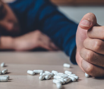 the person using drug overdoses lying on the table. close up on pills in hand.