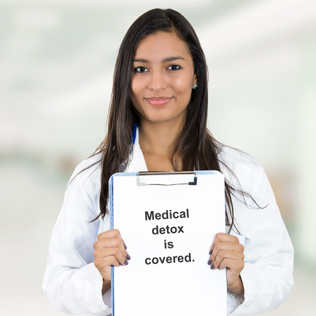 Doctor with sign that reads "Medical Detox is covered."